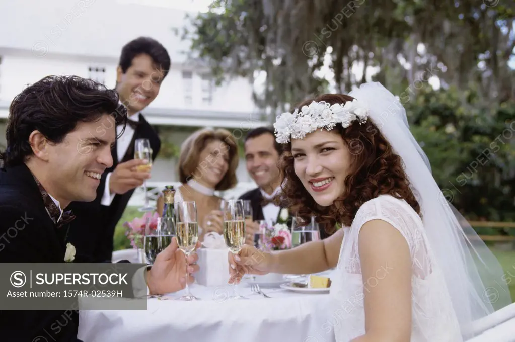 Portrait of a newlywed couple and their friends toasting with champagne glasses