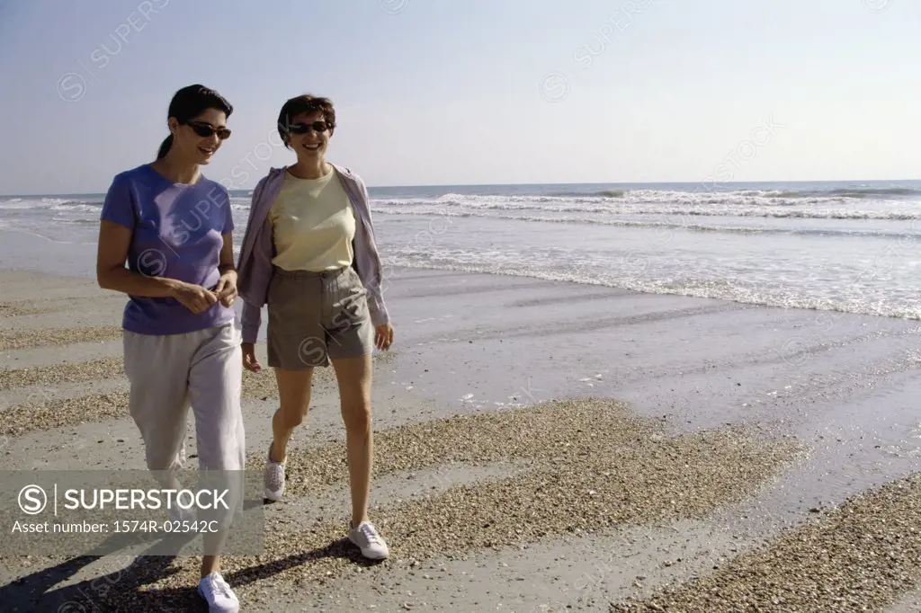Two mid adult women walking on the beach