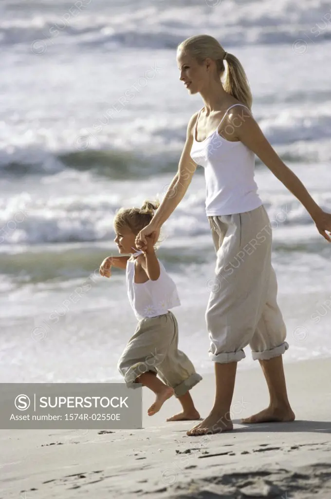 Side profile of a mother and her daughter walking on the beach