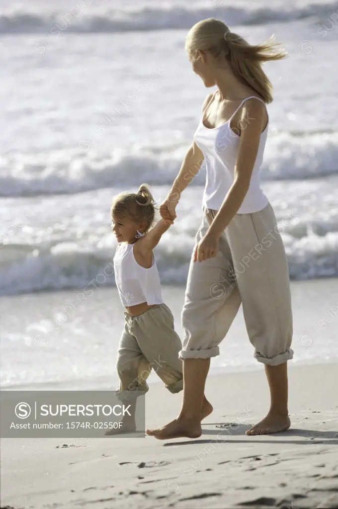 Side profile of a mother and her daughter walking on the beach