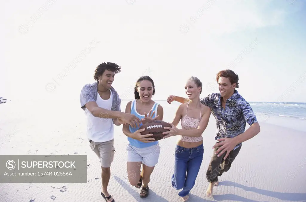Two teenage couples playing football on the beach