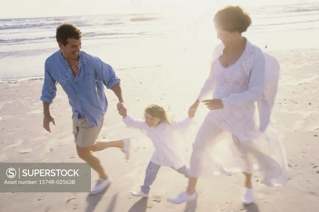 Parents running on the beach with their daughter