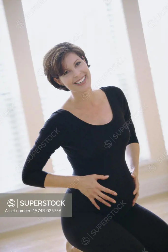 Portrait of a pregnant woman touching her abdomen