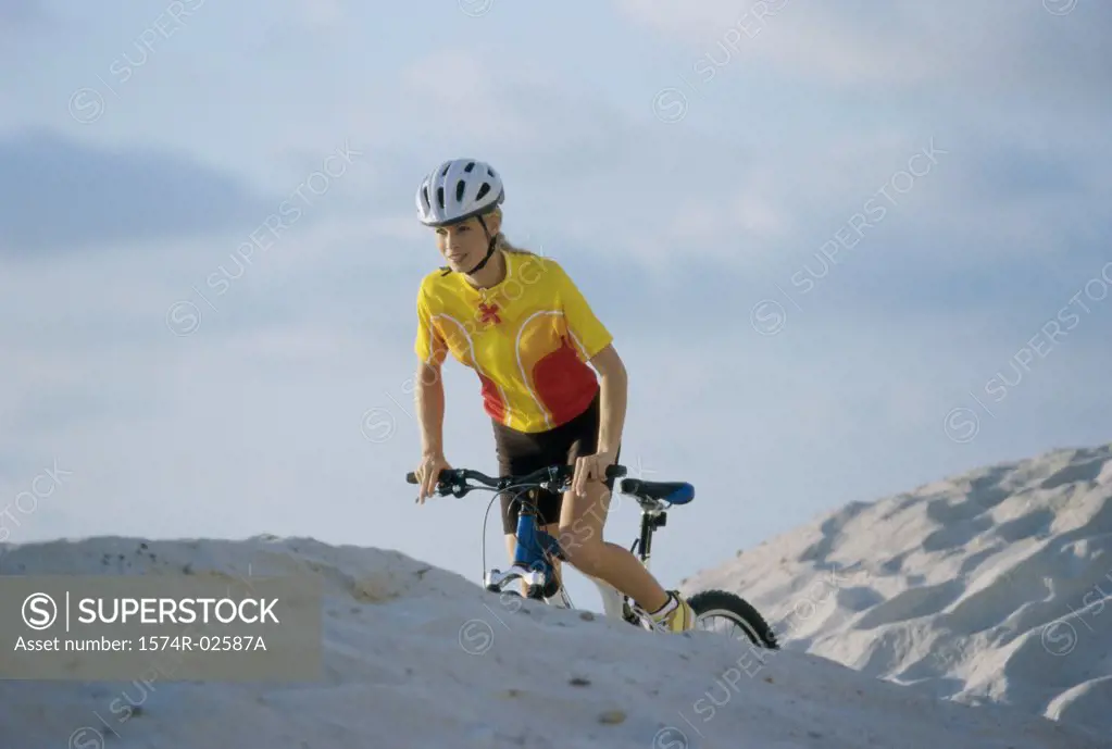 Young woman cycling on sand