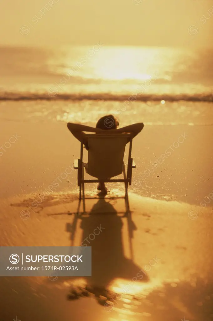 Silhouette of a young woman sitting in a chair on the beach