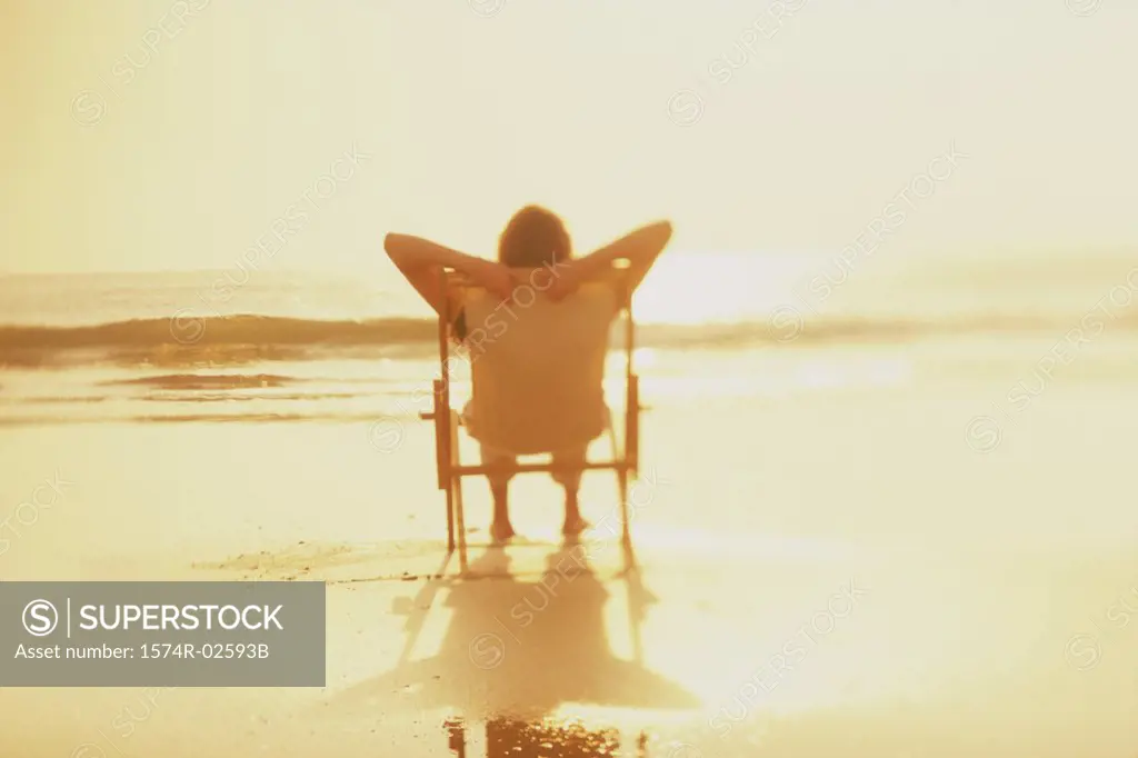 Silhouette of a young woman sitting in a chair on the beach