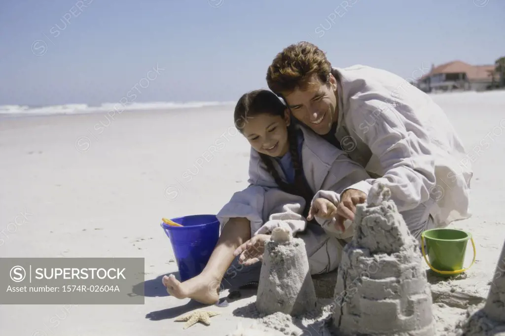 Father and his daughter making sand castles on the beach