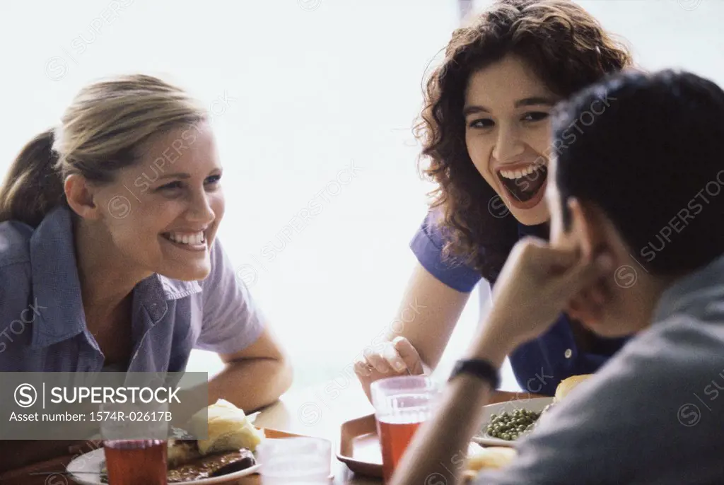 Two young women and a young man sitting in a restaurant
