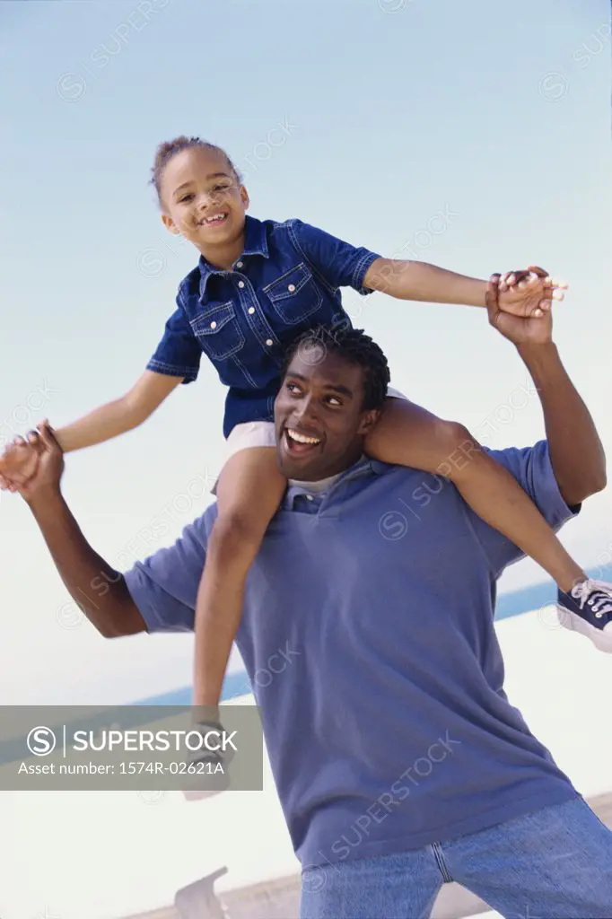Portrait of a father carrying his daughter on his shoulders