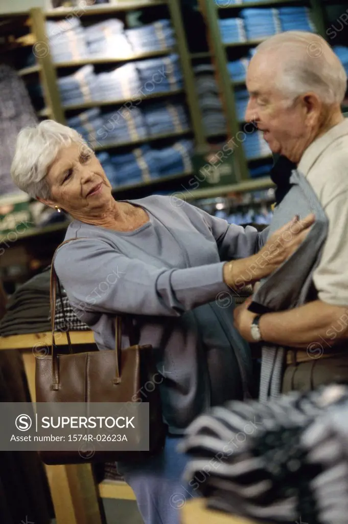 Senior woman holding a t-shirt against a senior man in a clothing store