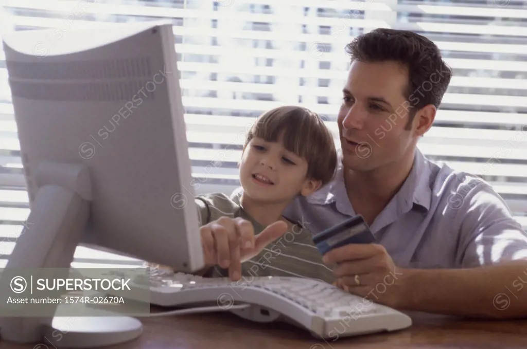Father and his son sitting in front of a computer
