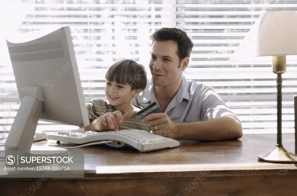 Father and his son sitting in front of a computer