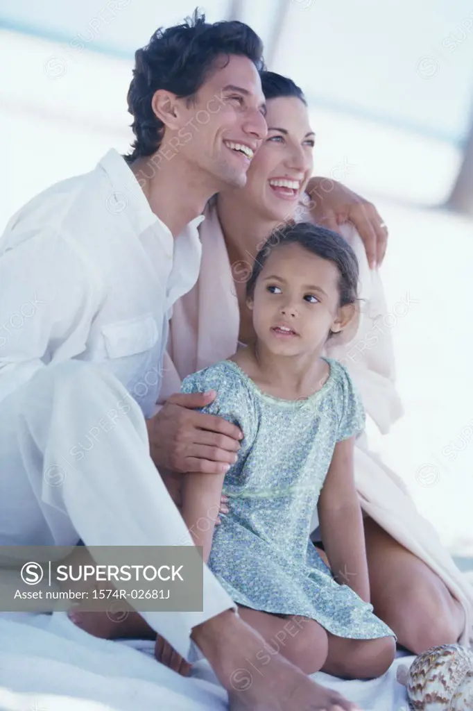 Parents sitting with their daughter on the beach
