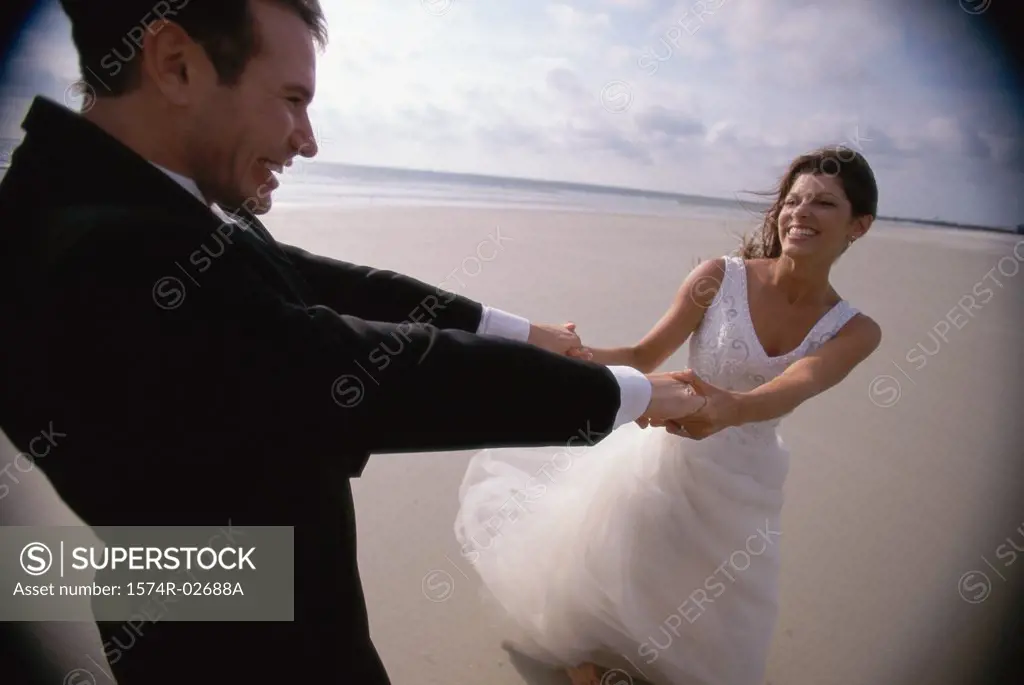Newlywed couple spinning each other on the beach