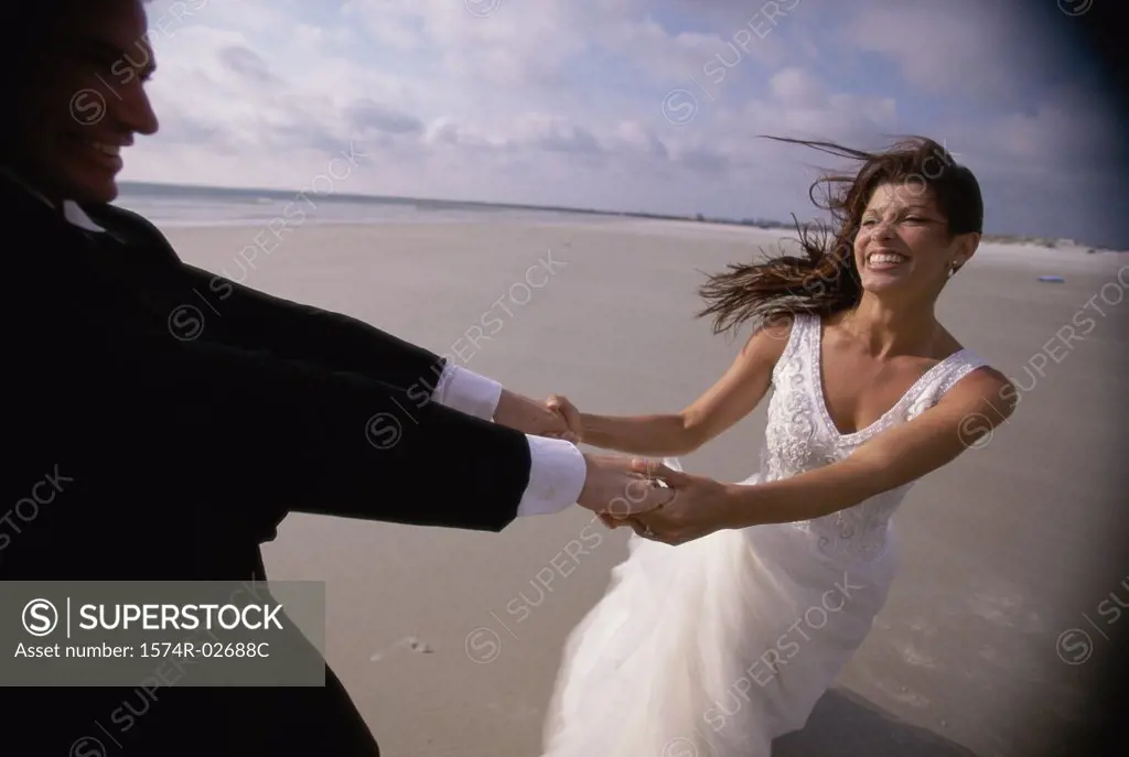 Newlywed couple spinning each other on the beach