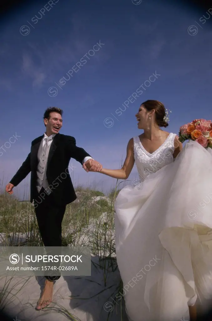 Newlywed couple walking on sand