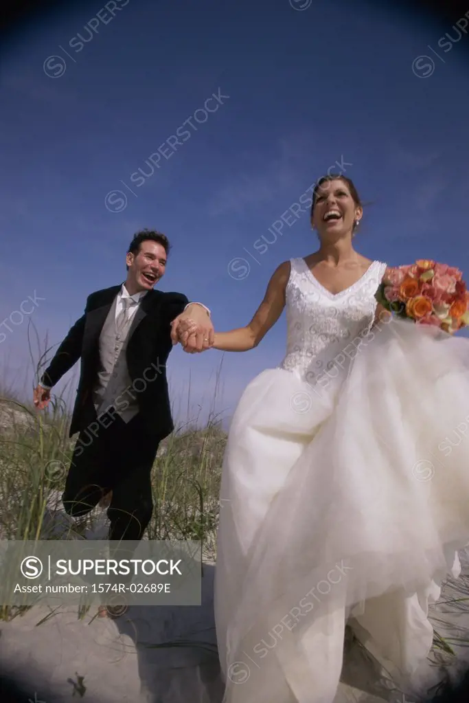 Newlywed couple running on sand