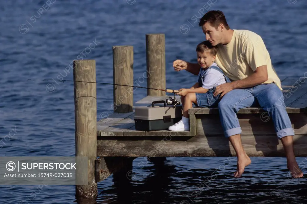 Father and his son sitting on a pier fishing