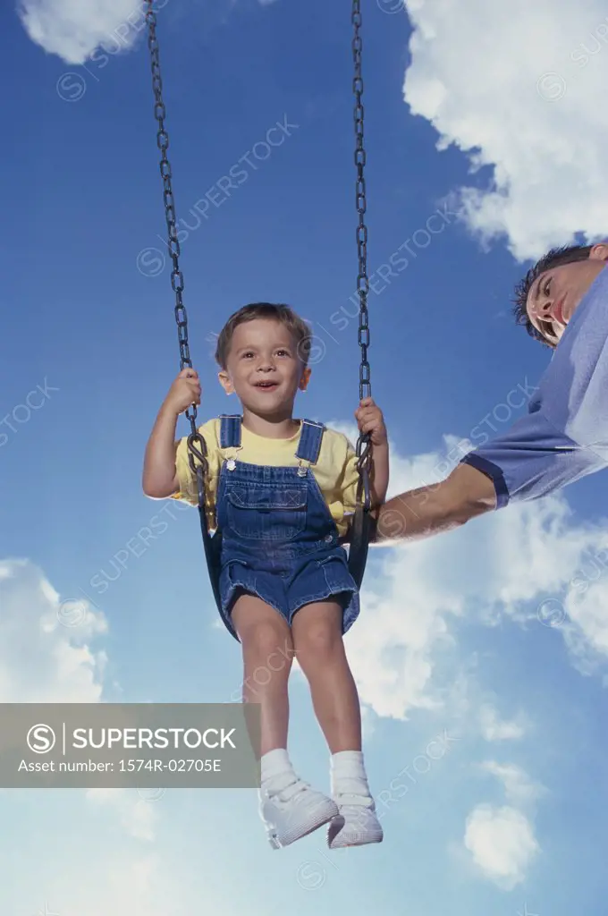 Low angle view of a father pushing his son on a swing