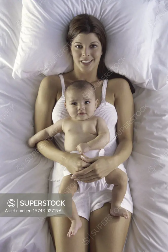 High angle view of a mother lying on a bed with her baby boy