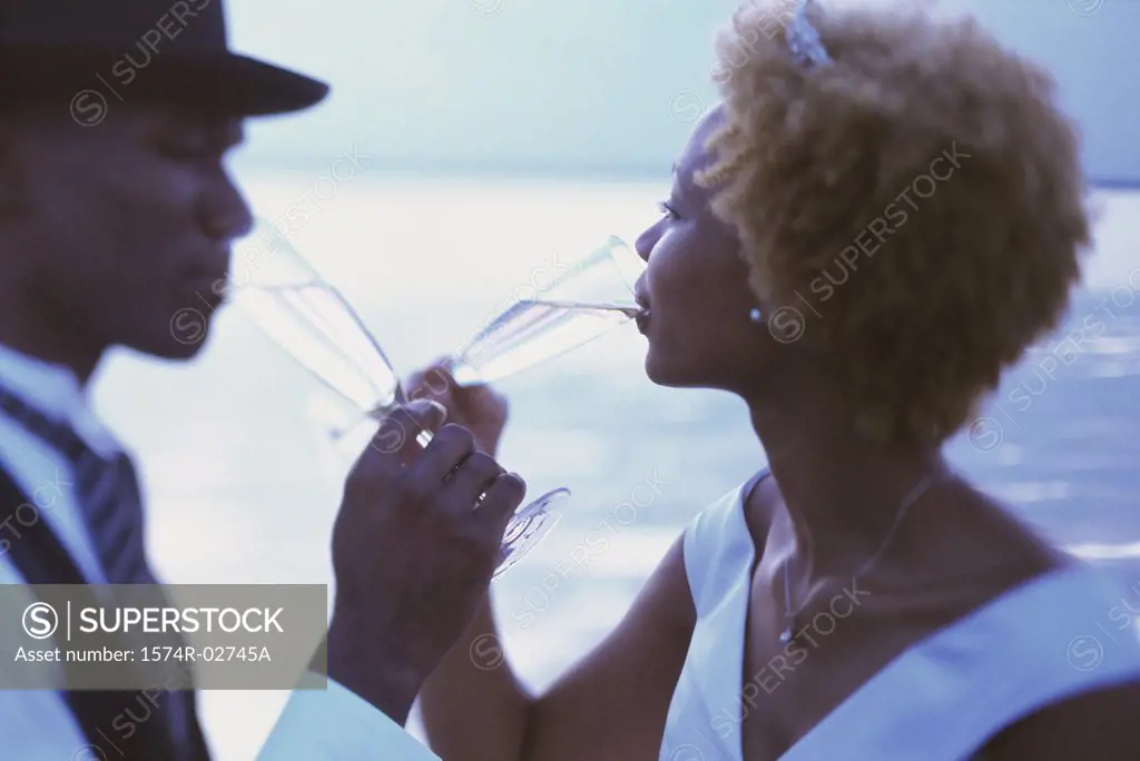 Side profile of a newlywed couple drinking champagne on the beach