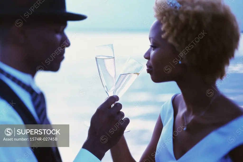 Side profile of a newlywed couple drinking champagne on the beach