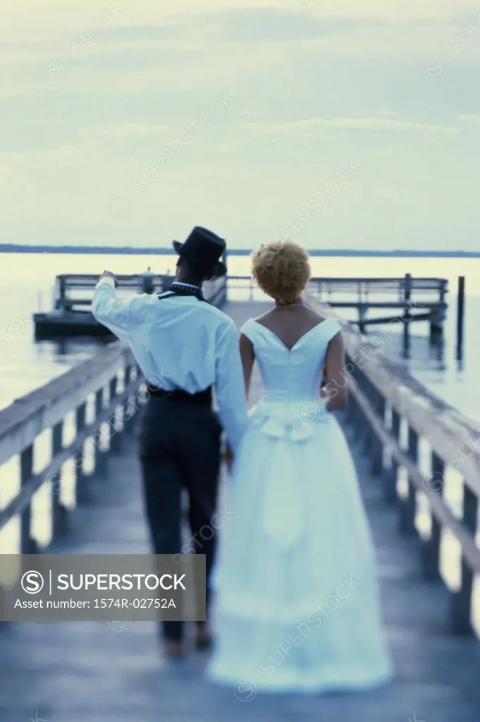 Rear view of a newlywed couple walking on a pier