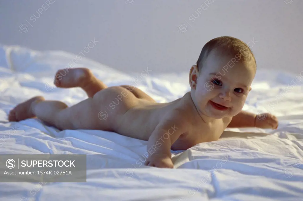 Baby girl lying on a bed and smiling