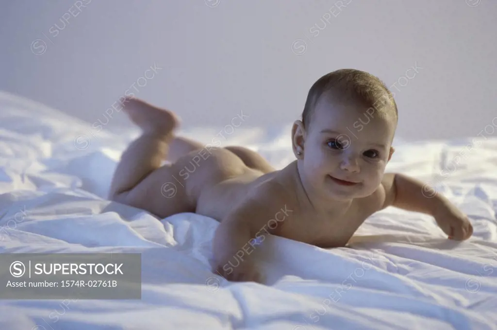 Baby girl lying on a bed and smiling