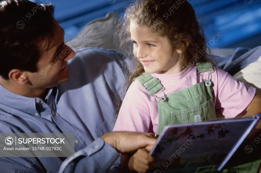 Close-up of a father and his daughter reading a book