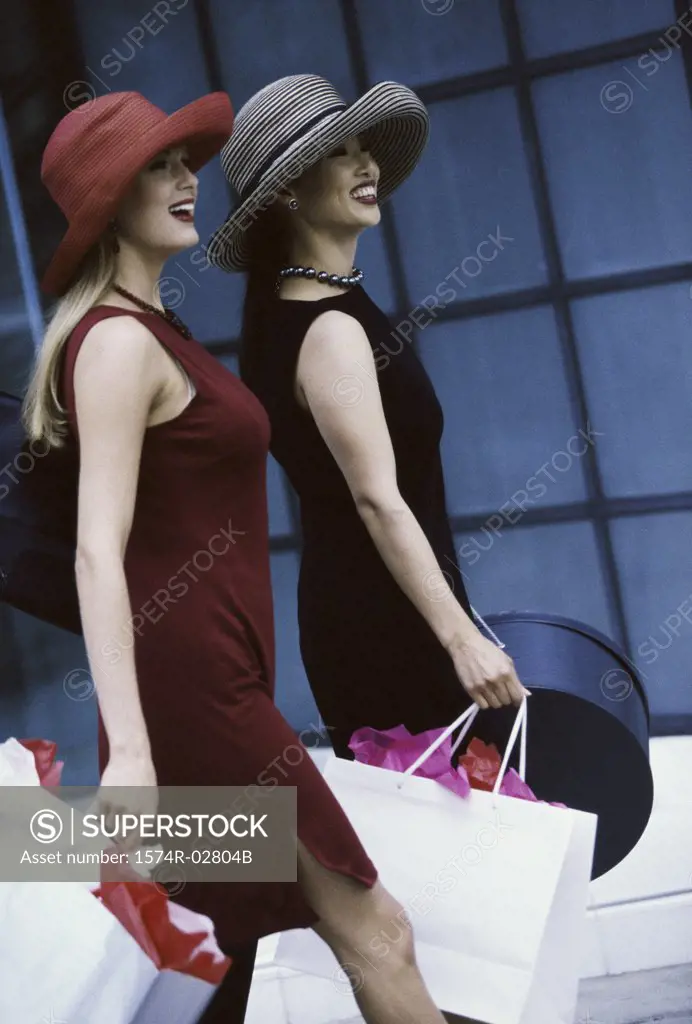 Side profile of two young women walking with shopping bags
