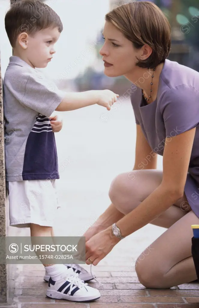 Side profile of a mother tying her son's shoelaces