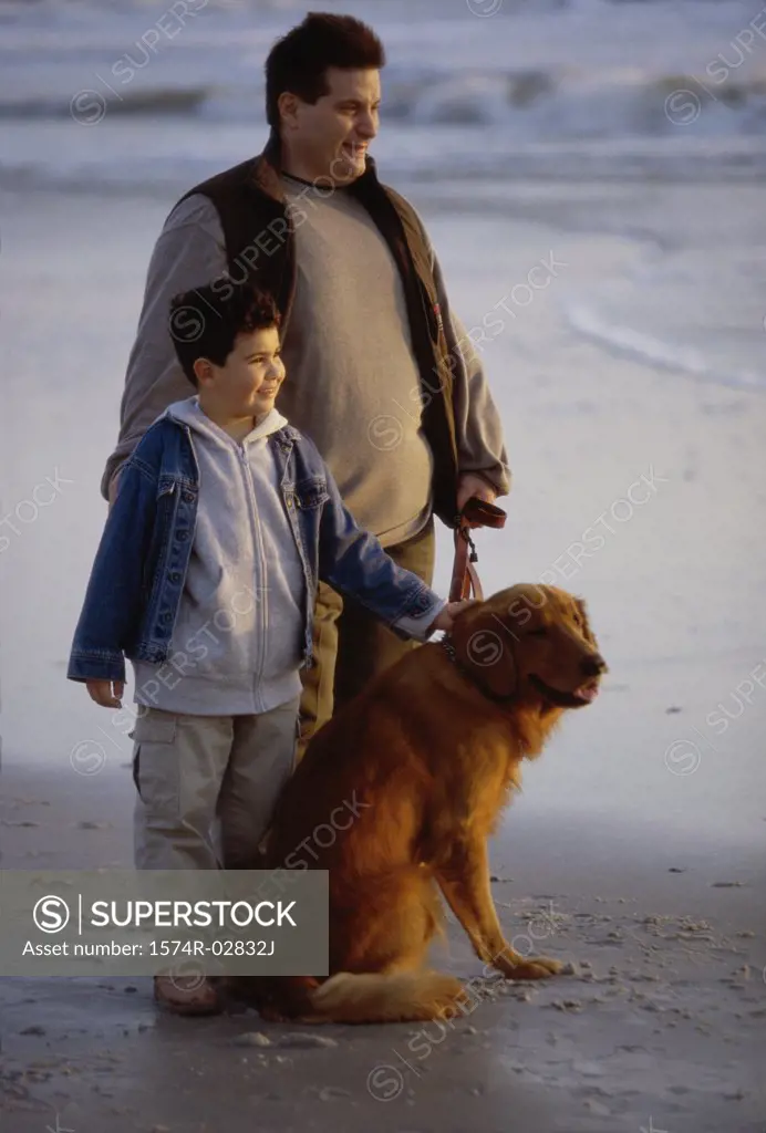 Father and his son with their dog on the beach