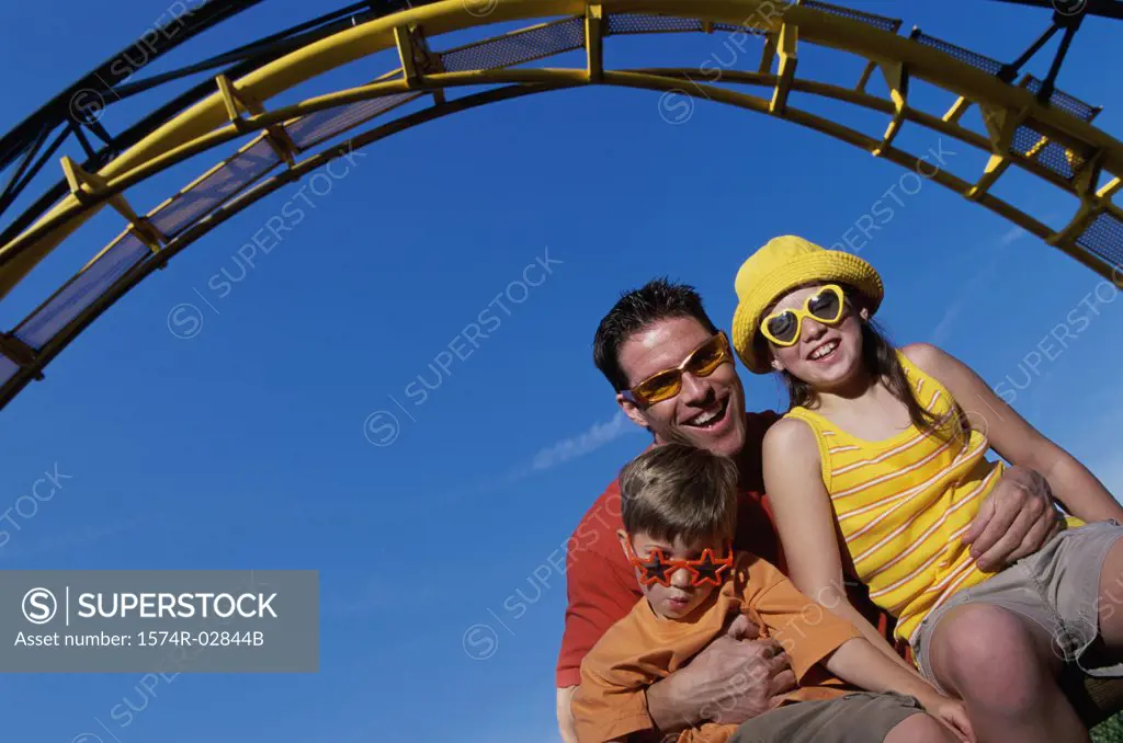 Portrait of a father with his son and daughter on an amusement park ride
