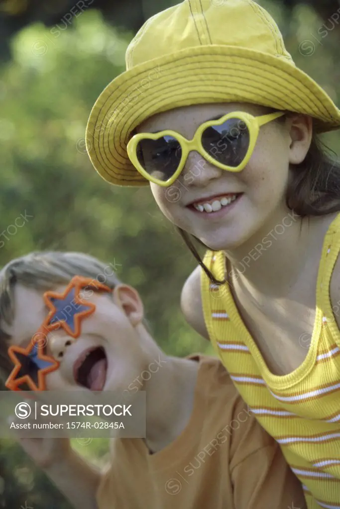 Portrait of a boy and a girl wearing sunglasses making a face