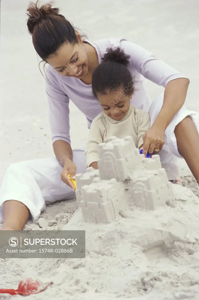 Mother and her daughter making a sand castle on the beach