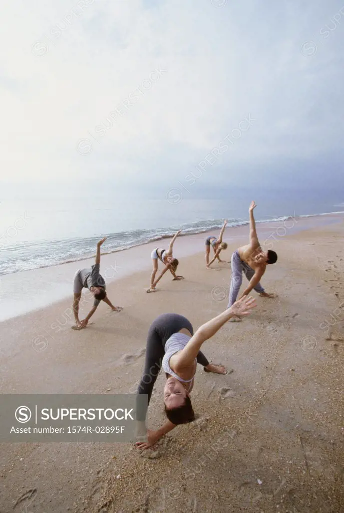 Group of people performing yoga on the beach