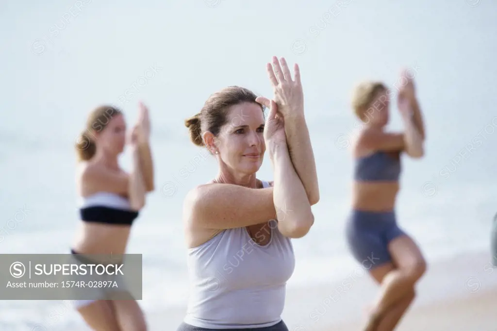 Group of people performing yoga on the beach