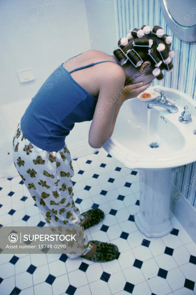 Young woman washing her face in a washbasin