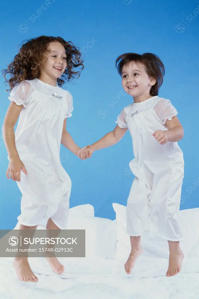 Two girls jumping on a bed