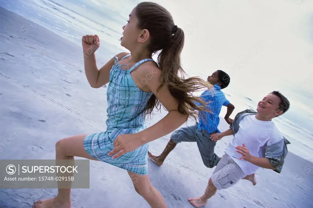 Two boys and a girl running together on the beach