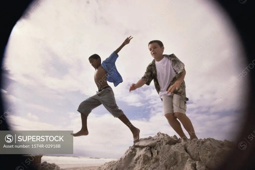 Low angle view of two boys jumping on the beach