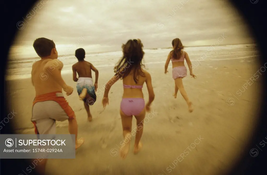 Rear view of a group of children running on the beach