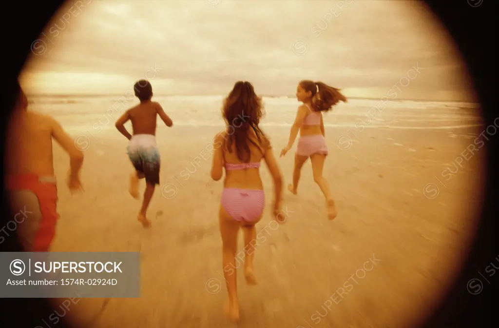 Rear view of a group of children running on the beach