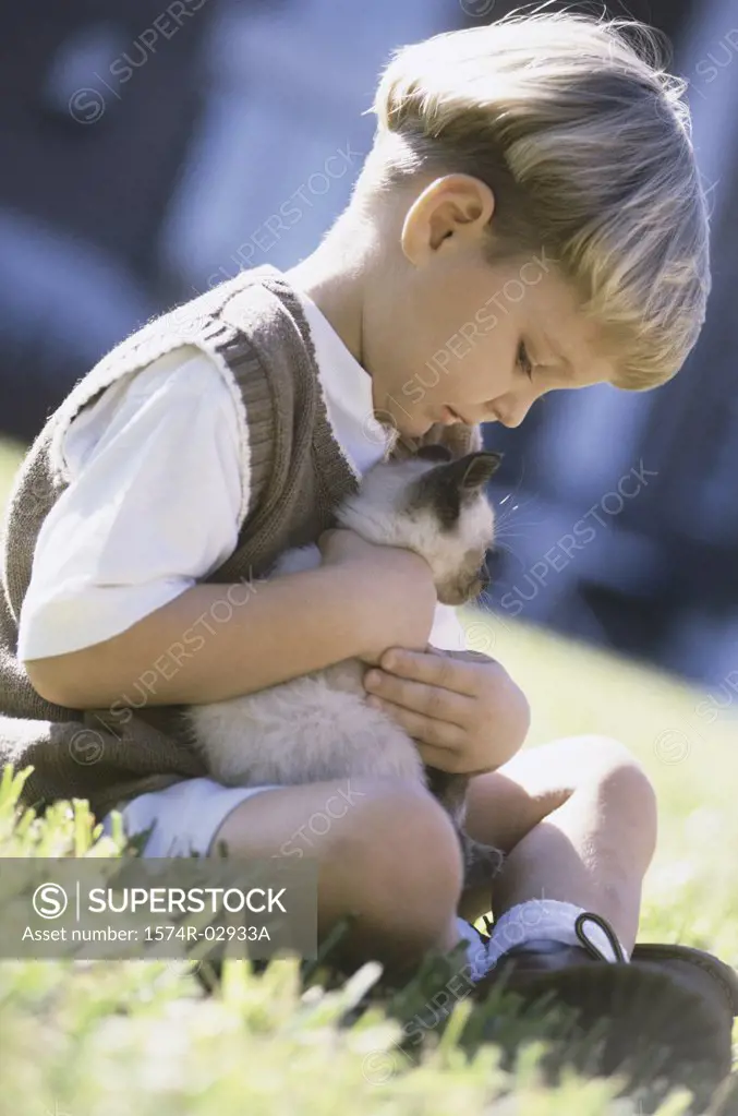 Side profile of a boy holding a Siamese kitten