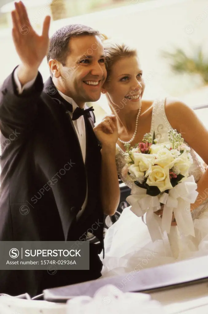 Newlywed couple waving from a convertible car