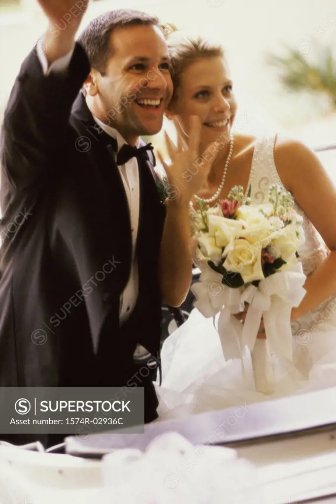 Newlywed couple waving from a convertible car