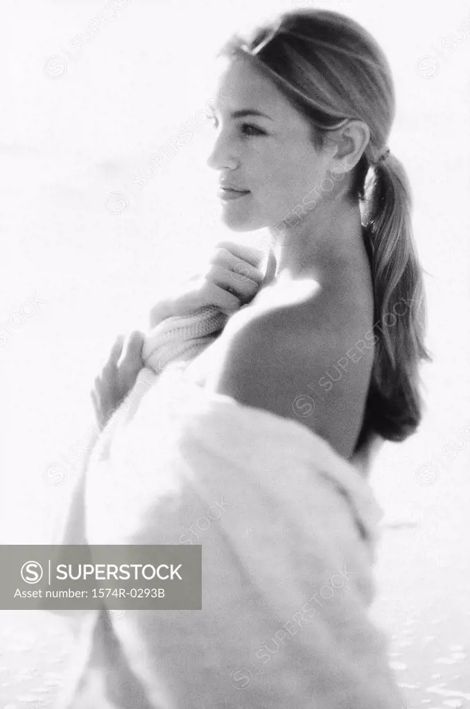 Side profile of a young woman wrapped in a towel on the beach