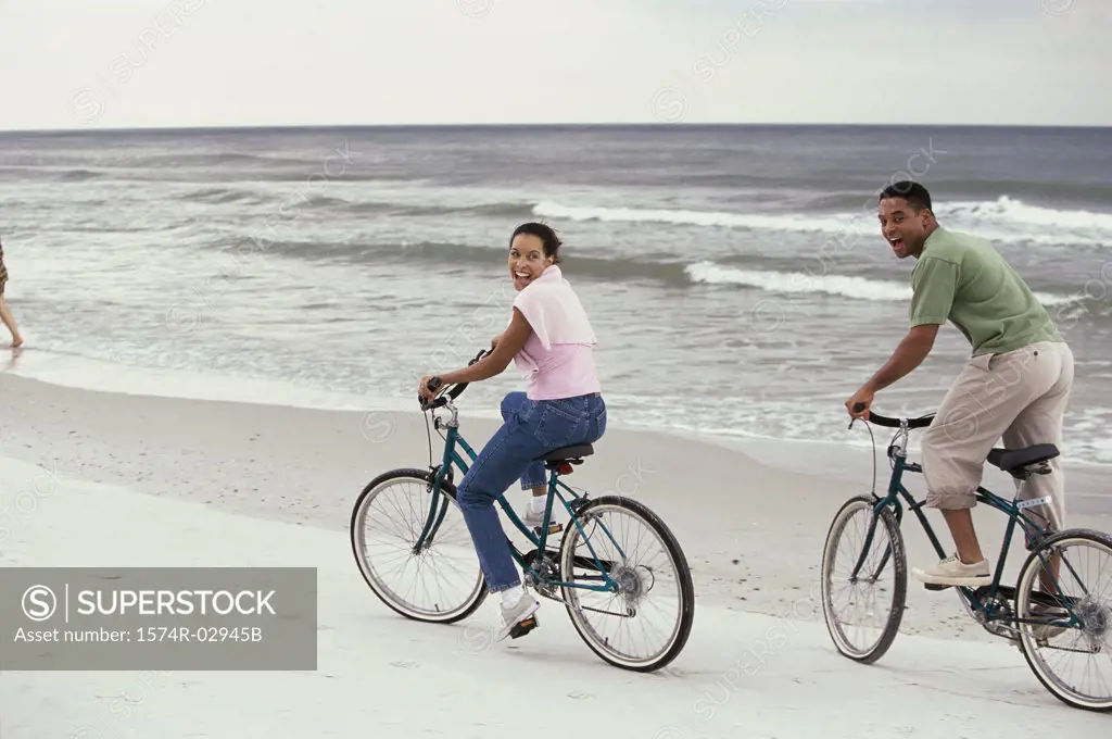 Young couple cycling on the beach