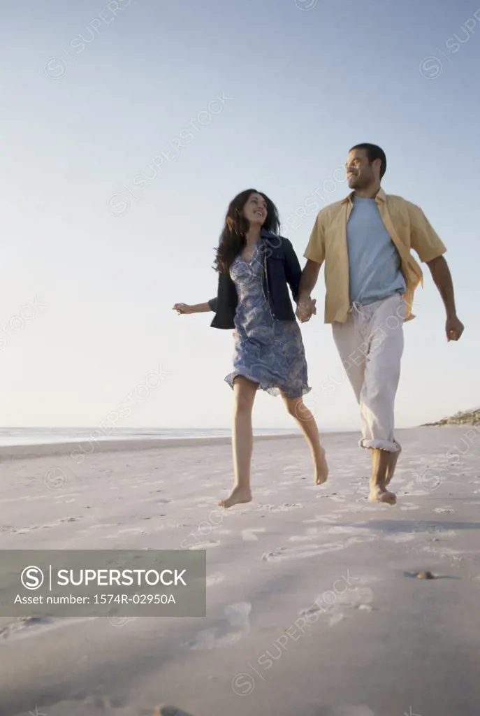 Low angle view of a young couple running together on the beach